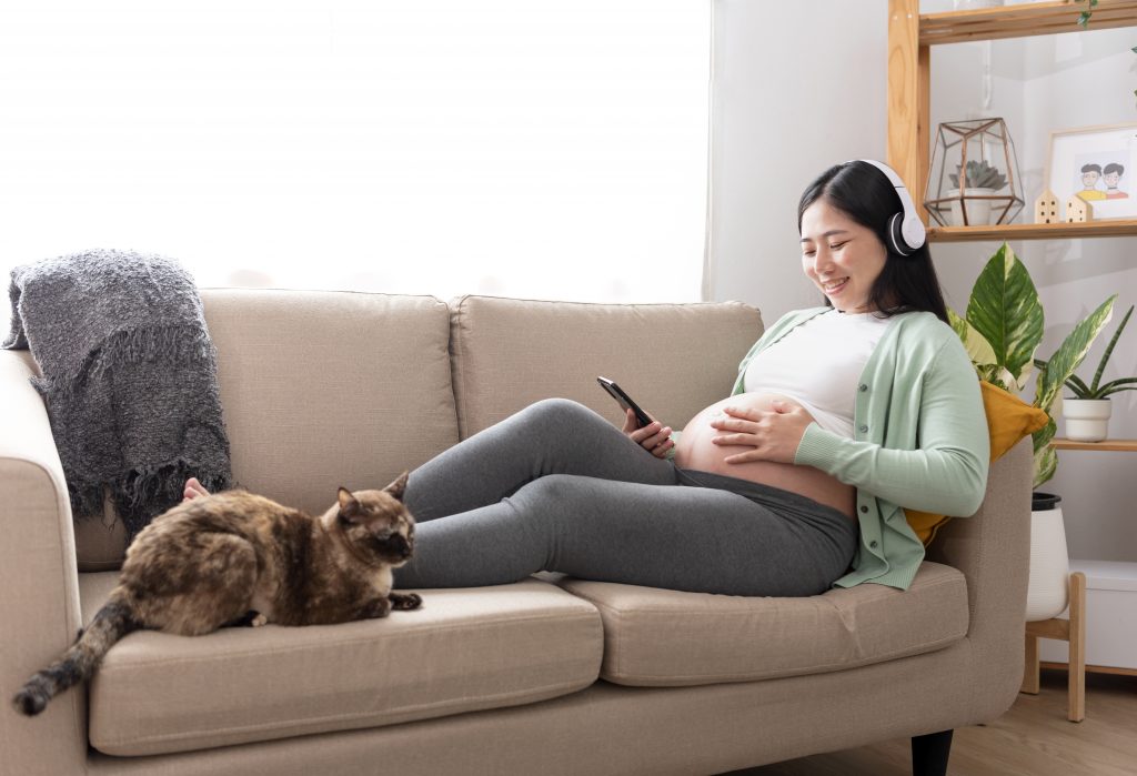 Asian beautiful pregnant woman hands fondle on belly and listeni